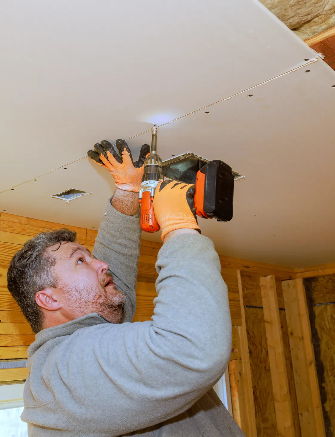 Contractor installing drywall ceiling during a room addition project in Dallas TX