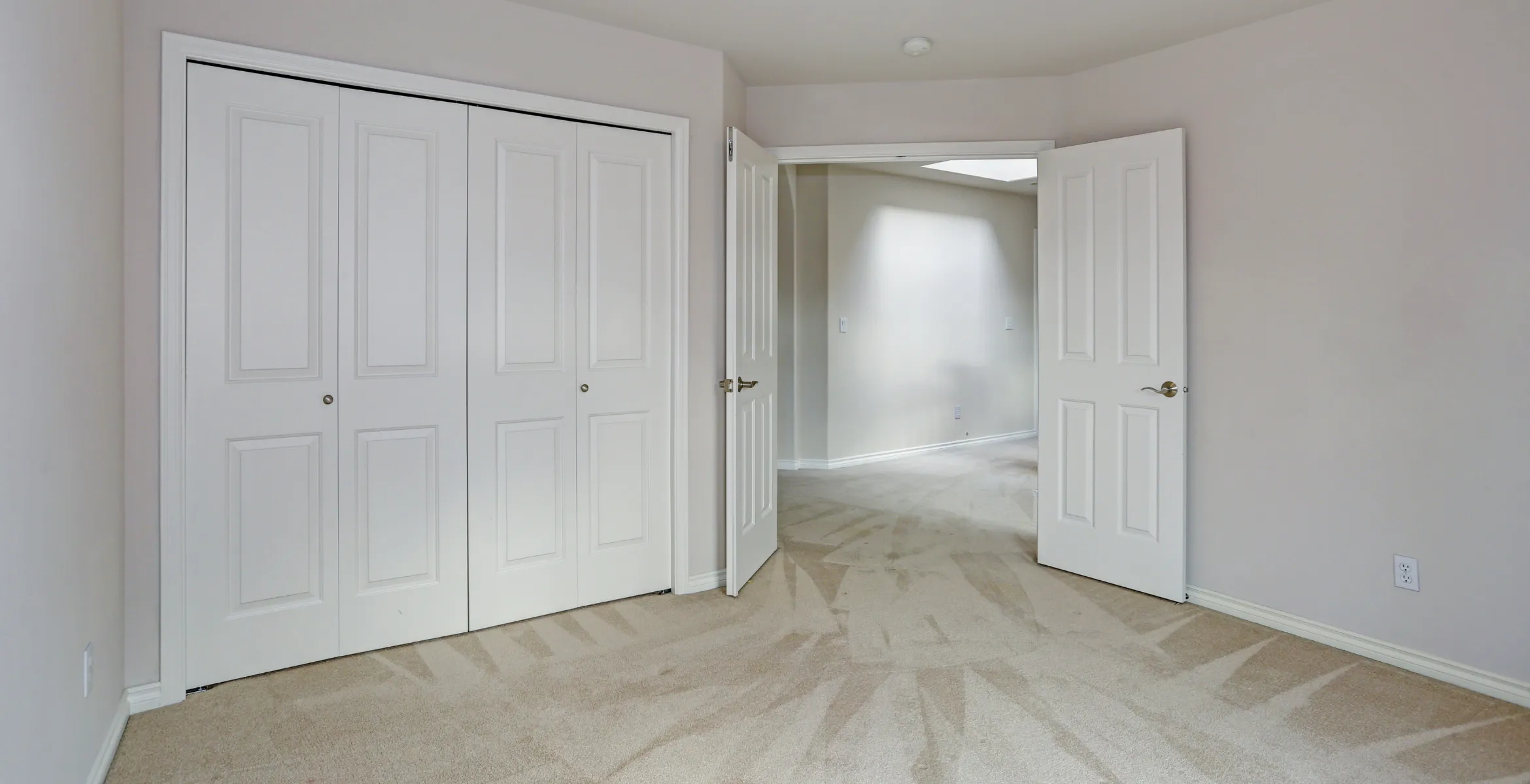Second story bedroom addition in Dallas TX showcasing new carpet flooring, built-in closet doors, and smooth transition into an adjacent living space.
