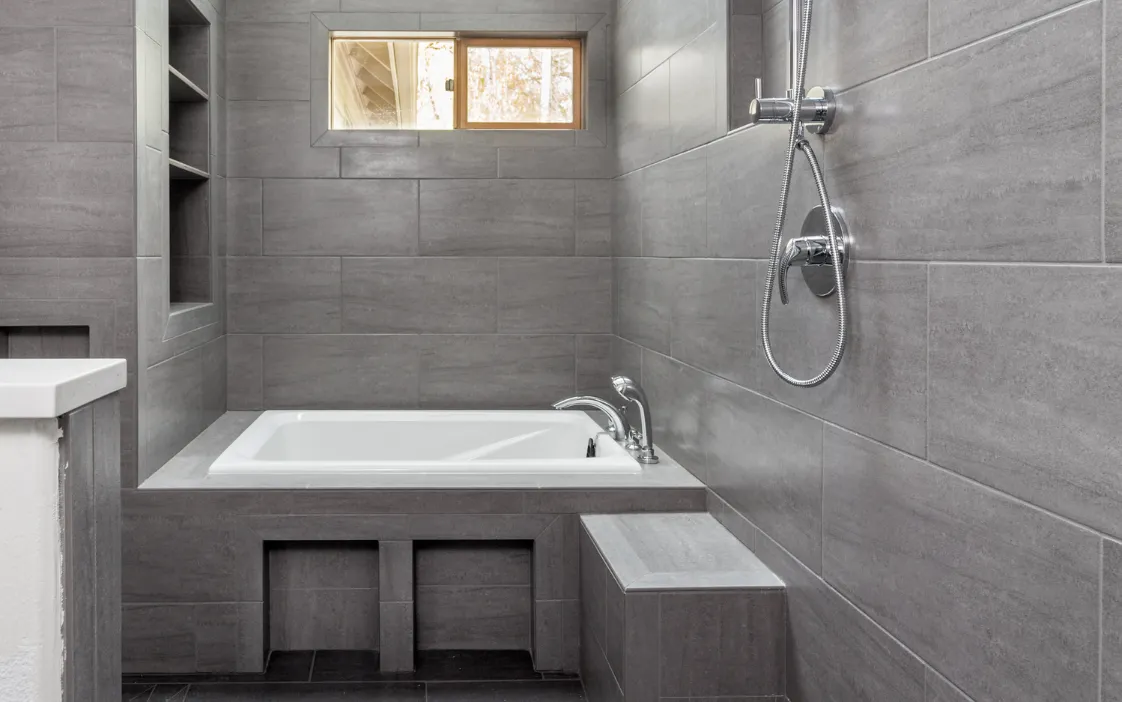 Finished bathroom addition with modern tile, bathtub, and shower in a Dallas home