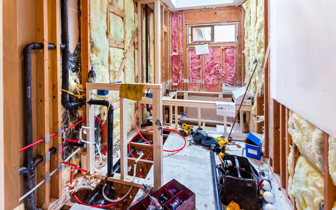 Bathroom addition under construction showing plumbing rough-in and wall framing in a Dallas home
