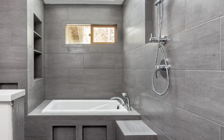 Modern new bathroom addition featuring tiled walls, bathtub, and shower in a Dallas home